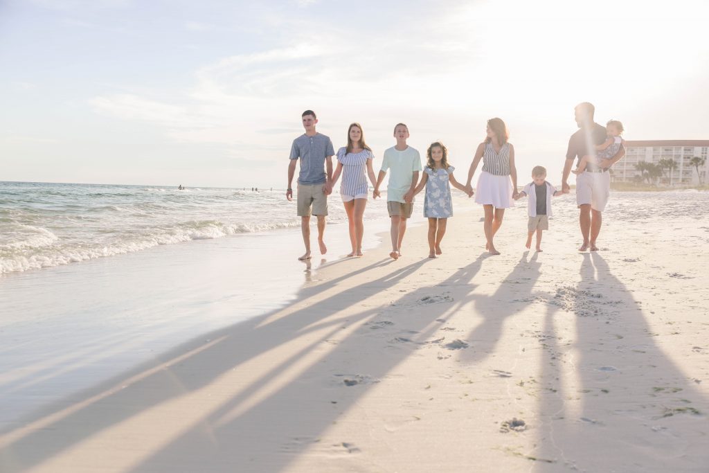 Family walking hand in hand down the beach in Fort Walton Beach, FL