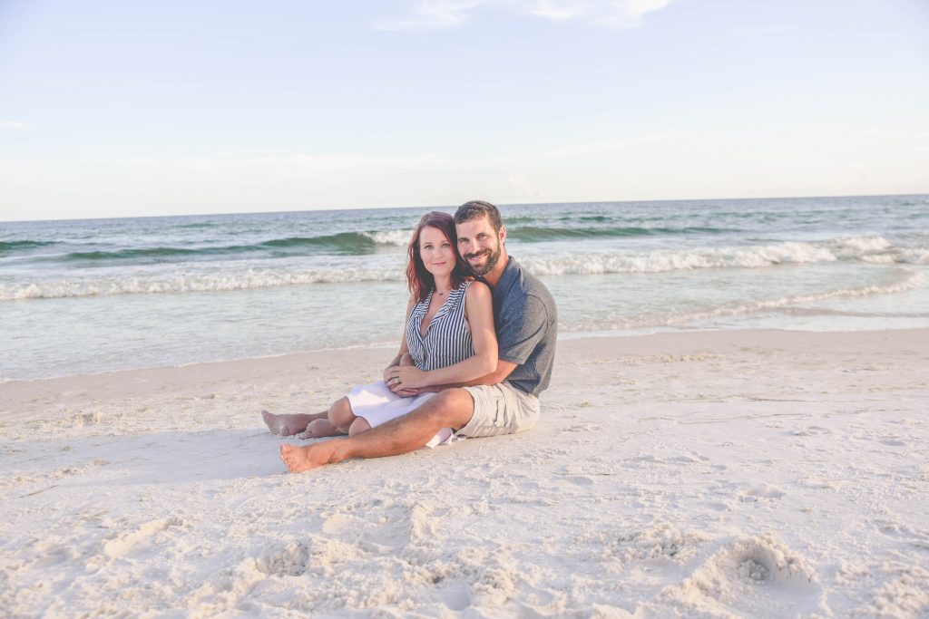 Couple holding each other while sitting on the beach in Fort Walton Beach, FL
