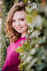 High School Senior teen smiling at the camera with greenery