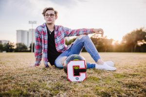 Male teen posing with a soccer ball for senior portraits in Destin, FL.