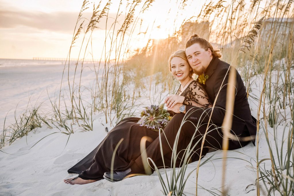 Bride and groom sitting on navarre beach during the 'golden hour'