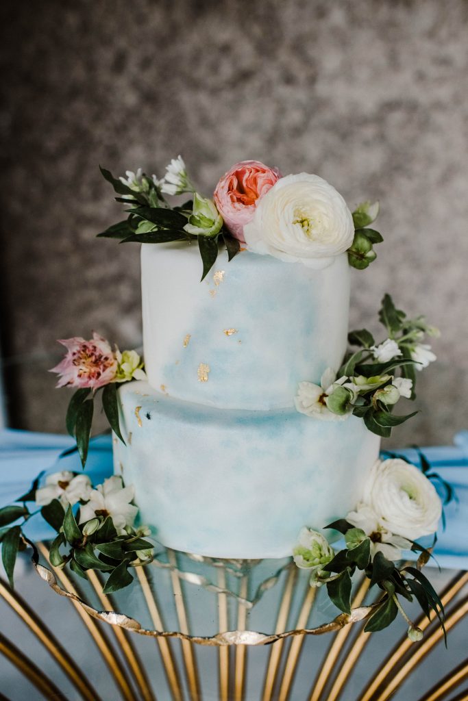 Watercolor wedding cake with beautiful florals displayed on a gold cake stand