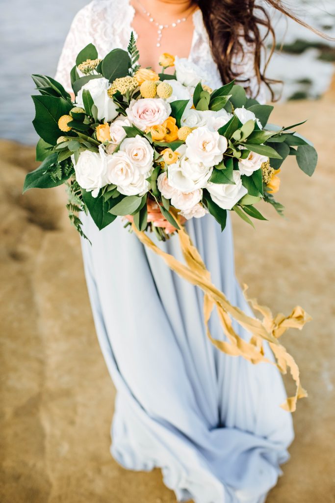 oversized bridal bouquet featuring yellow, white, and pastel pink florals for a vow renewal at Sunset Cliffs, CA. 