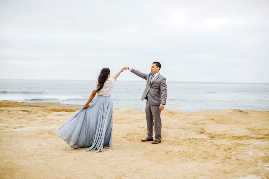 Groom twirling his beautiful bride at sunset cliffs in San Diego, CA