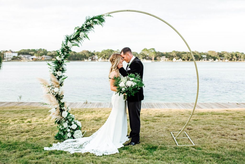 Metal Gold circular wedding arbor dressed up with greenery and white florals designed by destin florist, Destin floral Designs. 